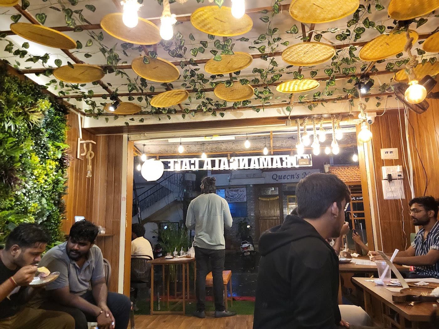 Inside the cafe: wooden tables under a ceiling of leaves and hanging lamps