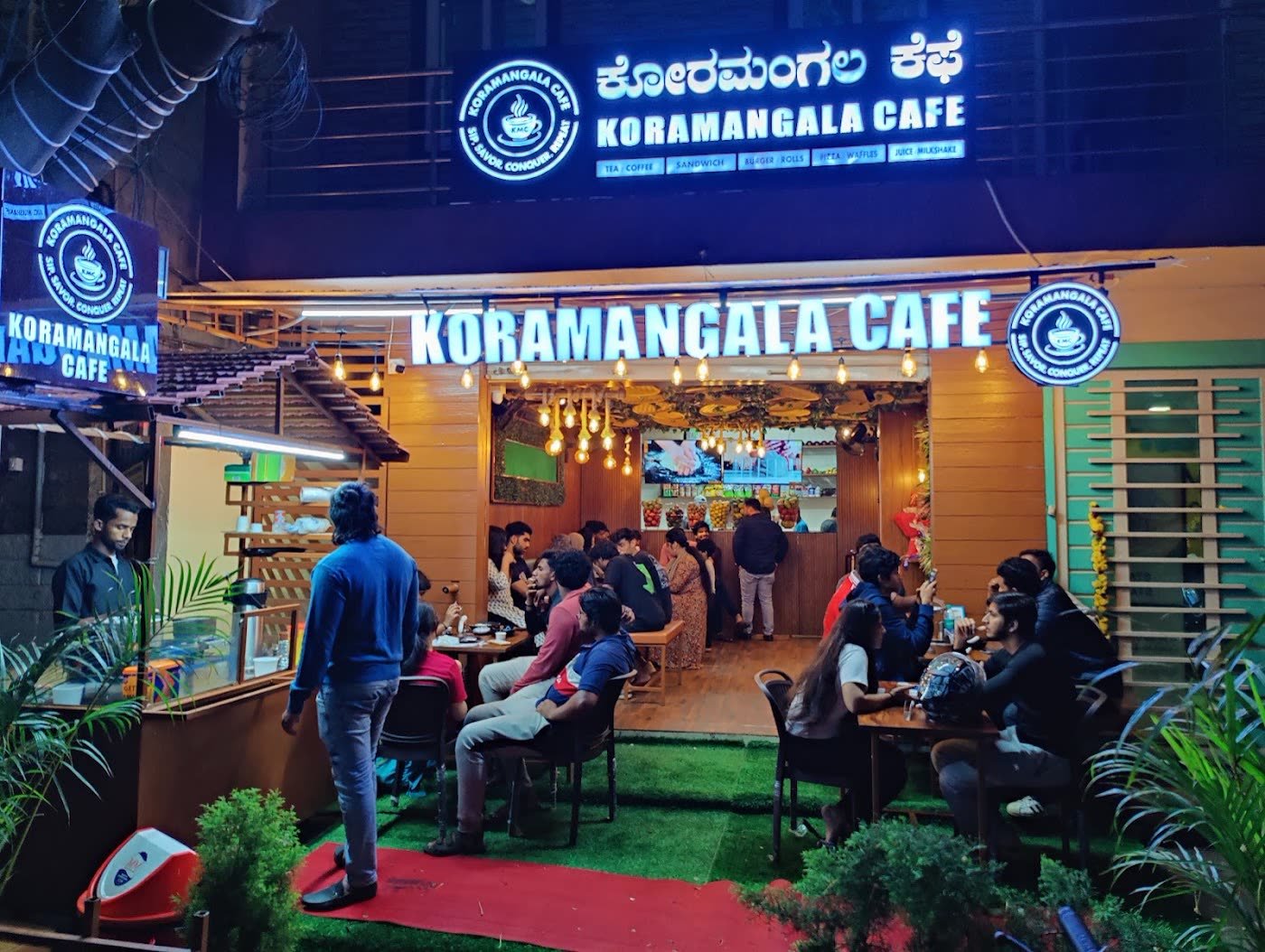 The cafe front at night with its blue neon sign